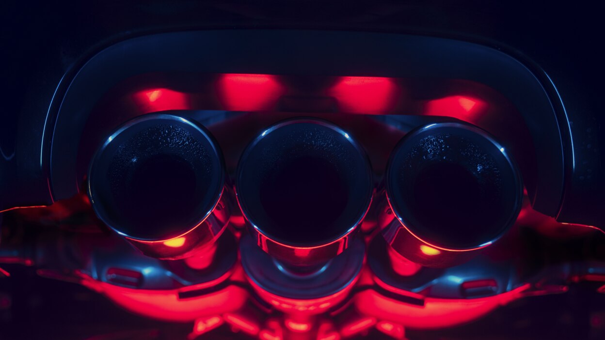 Gros plan de l’échappement triple central d’une Integra Type S. L’image est saturée de lumière rouge et bleue.