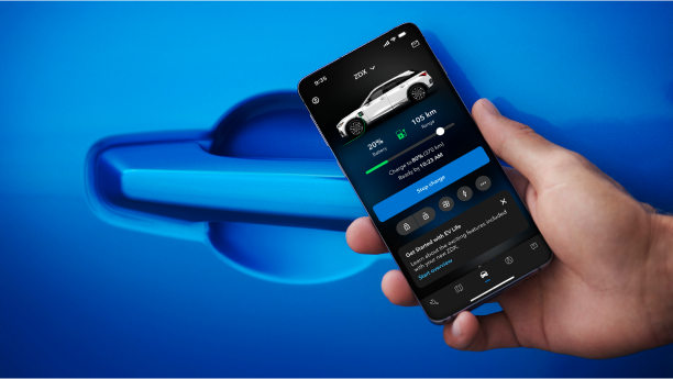 Close up of a hand holding a smartphone, on an Acura EV app page, in front of the door handle of a blue Acura ZDX.